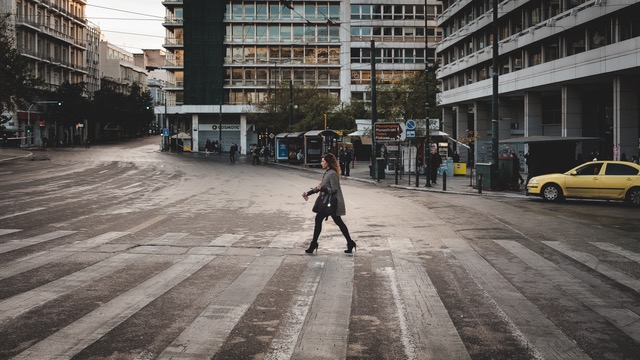 אישה חוצה כביש ברחוב שהעסקים בו סגורים